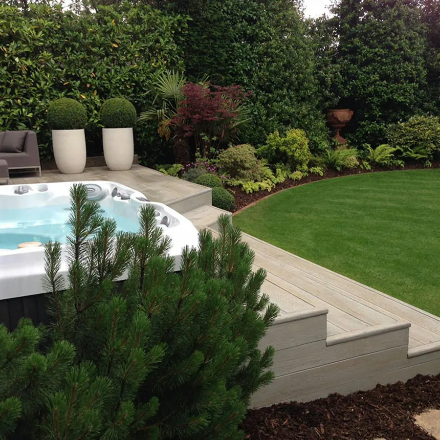 A hard-shell hot tub set into decking in a leafy English garden